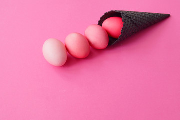 The eggs roll out of the black horn. Pink background.