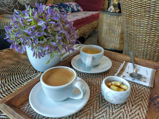 Set of hot coffee hot tea and biscuits on wicker weave table