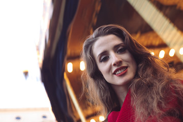 Portrait of a beautiful young girl in front of a carousel horse