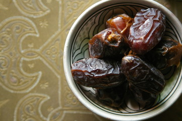Dates in a bowl on ethnic metal plate. Ramadan kareem.