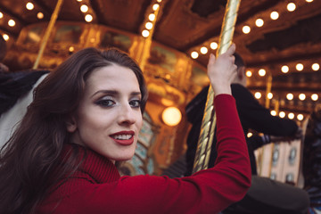Portrait of a beautiful young girl in front of a carousel horse