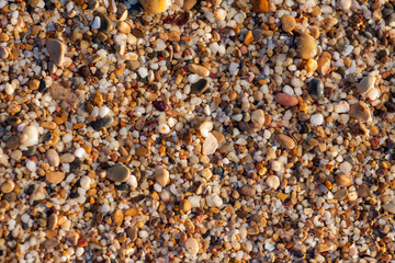 sea pebbles colored granite on the beach background stones. The shore of the beach with sand and pebbles washed by the waves of the sea.
