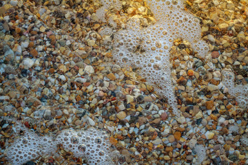 sea pebbles colored granite on the beach background stones. The shore of the beach with sand and pebbles washed by the waves of the sea.