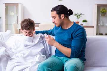 Fototapeta premium Young father caring for sick son