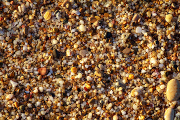 sea pebbles colored granite on the beach background stones. The shore of the beach with sand and pebbles washed by the waves of the sea.