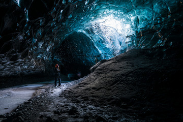 Female explorer inside ice cave tunnel, Iceland