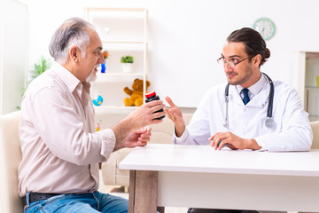 Obraz premium Young male doctor visiting old patient at home
