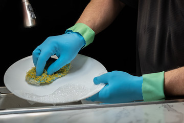 Close up of a model's hands washing dishes with light blue rubber gloves with anit-drip cuffs.