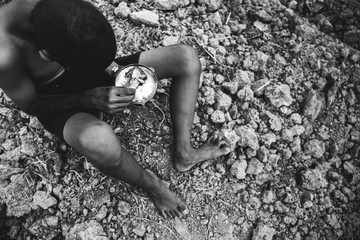 poor child or beggar begging you for help sitting at dirty slum. concept for poverty or hunger...
