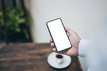Mockup image blank white screen cell phone.man hand holding texting using mobile on desk at office.background empty space for advertise text.people contact marketing business,technology 