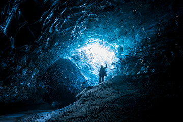 Female explorer standing inside ice cave tunnel, Iceland - Powered by Adobe