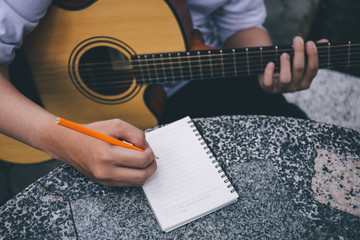 Fototapeta premium artist songwriter thinking writing notes,lyrics in book at studio.man playing live acoustic guitar relax chill.concept for musician creative.composer work process.people relaxing time with instrument