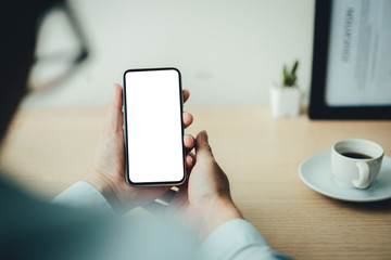 Mockup image blank white screen cell phone.man hand holding texting using mobile on desk at coffee shop.background empty space for advertise text.people contact marketing business,technology 