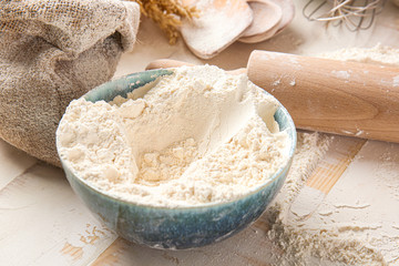 Bowl with flour and rolling pin on table