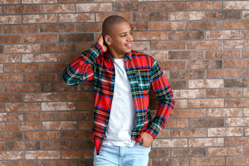 Stylish African-American man near brick wall