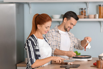 Happy couple cooking together in kitchen