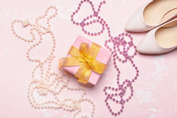 Beautiful gift with beads and high-heels on color background. International Women's Day celebration
