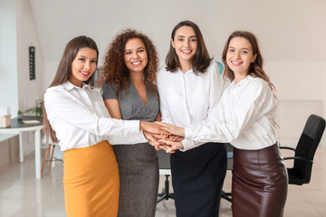 Young women putting hands together in office. Concept of feminism