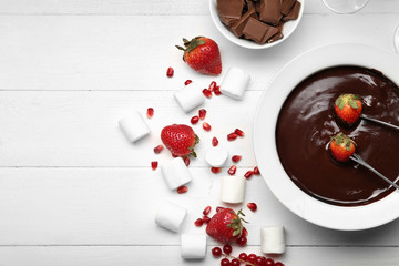 Bowl with tasty chocolate fondue, berries and marshmallow on table