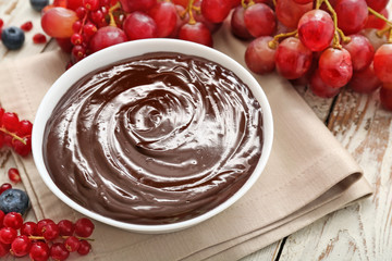 Bowl with tasty chocolate fondue and berries on table