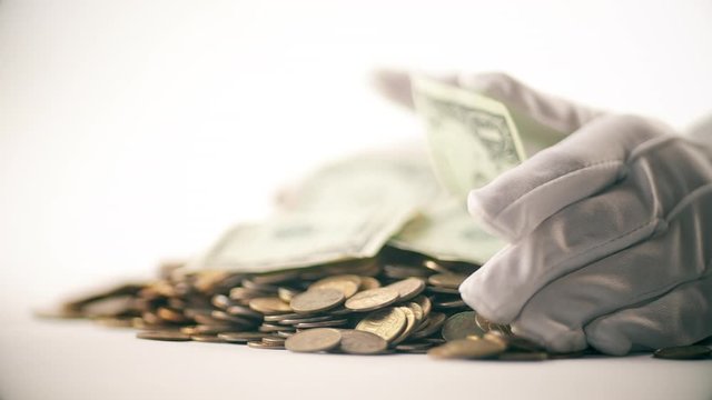 White-gloved hands scooping up a pile of gold coins. They sort out and scatter money.On white background. Garland. Money glitters.