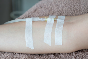 Patient with intravenous drip .receiving saline solution. Injecting needle in to the arm.
