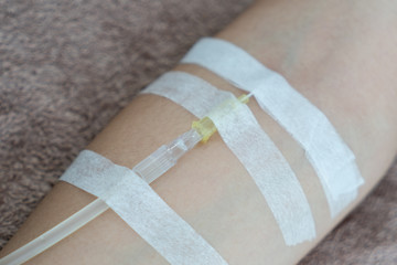 Patient with intravenous drip .receiving saline solution. Injecting needle in to the arm.