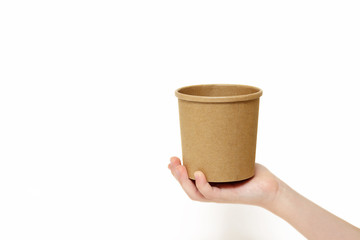 Eco kraft paper tableware. Children's hand holds a paper disposable container for soup isolated on white background. Recycling concept. Zero waste.