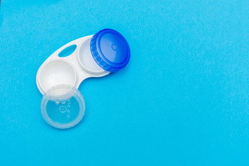 Contact lens case open on a bright blue flat lay background. Vision, healthcare, eye sight concepts.