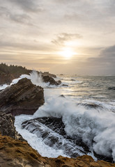 Sunset with stormy clouds and crashing waves at Shore Acres State Park, Charleston Oregon, USA