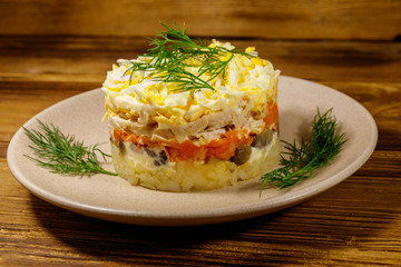 Tasty layered salad with potatoes, chicken breast, marinated mushrooms, carrots, eggs and mayonnaise on wooden table