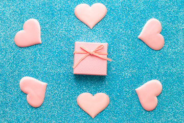 Obraz premium Valentines day pattern background flat lay pink hearts and a pink gift box with rose ribbon on a glittering classic blue background with copy space. love wedding romantic concept, minimal top view