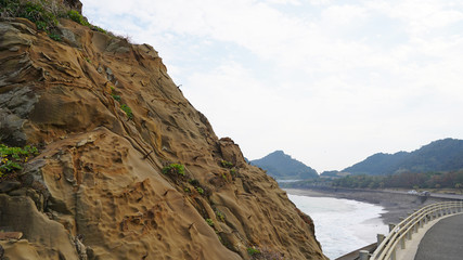 Volcanic coast of the Pacific Ocean, road along the overgrown mountains. Green vegetation on the...