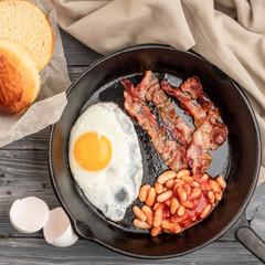 Fried eggs with bacon in a pan. Top view. Copy space.