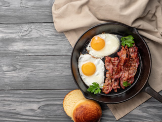 Fried eggs with bacon in a pan. Top view. Copy space.