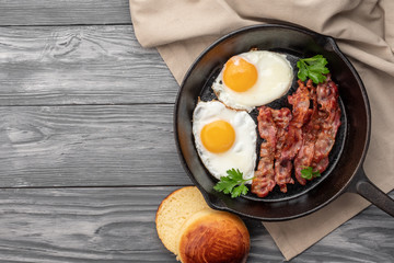 Fried eggs with bacon in a pan. Top view. Copy space.