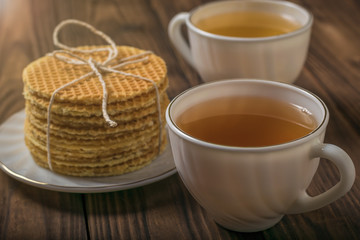 Two cups of tea and homemade waffles on a wooden table.