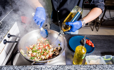 Chef cooking pasta with vegetables in pan. Italian style cuisine. Restaurant.