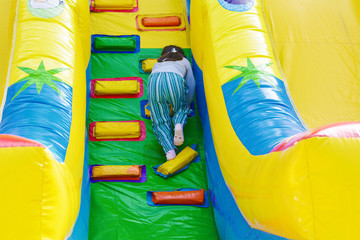 Fototapeta na wymiar Dangerous inflatable slide. Little girl climbing.