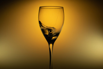 Water splash in glass on glowing background. splashing water in wine glass