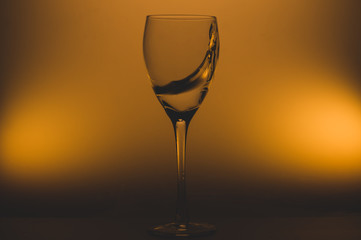 Water splash in glass on glowing background. splashing water in wine glass