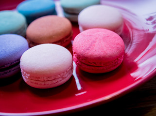 French colorful macarons on a red plate. Restaurant.