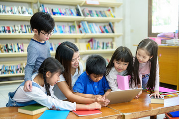 Group of Asian Student Kid Learning to use Laptop in Library with Women Teacher, Shelf of Books in Background, Asian Student Education Concept