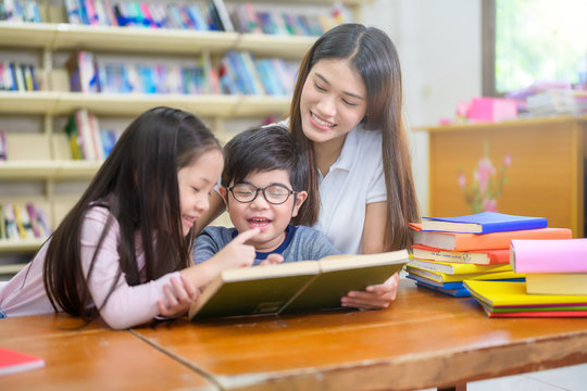 A Group of Asian Student Kid Reading a book with women teacher in School library with Shelf of Books in Background, Asian Kid Education Concept