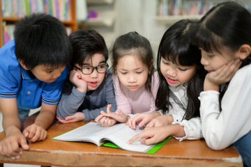 A Group of Asian Kids Reading Book in School Library with a Shelf of Book in Background, Asian Kid Education Concept