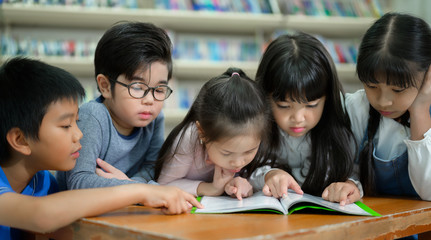 A Group of Asian Kids Reading Book in School Library with a Shelf of Book in Background, Asian Kid...