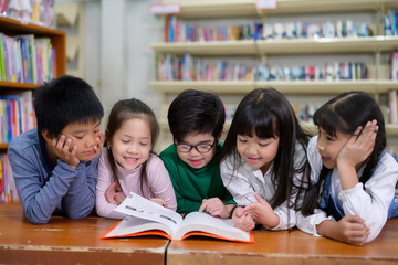 A Group of Asian Kids Reading Book in School Library with a Shelf of Book in Background, Asian Kid Education Concept - 314809366