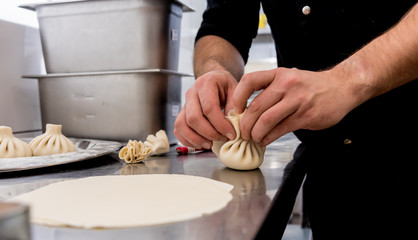 Chef coocking georgian khinkali or japanese wonton. Traditional meal of dough and meat. National cuisine, cooking process. Restaurant kitchen.