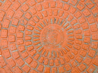  macro image of a bright orange plastic embossed manhole cover 