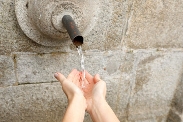 water fountain with splashing water on hands, outside with one person and horizontal, close up